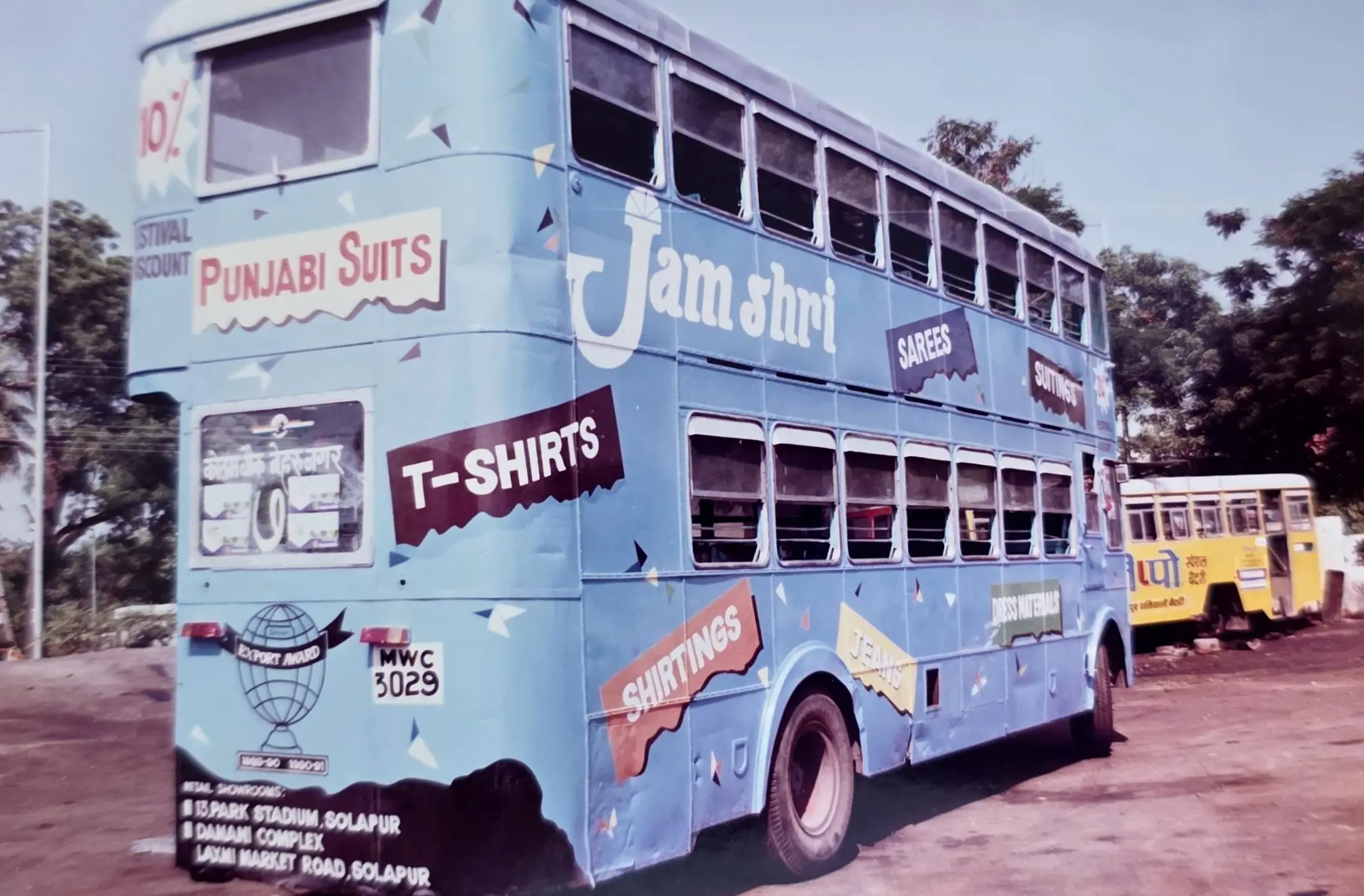 A double-decker bus hand-painted as a travelling Jamshri showroom, its panels lettered with sarees, suitings, shirtings, dress materials, jeans and T-shirts